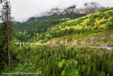 Rhätische Bahn in het Albula / Bernina landschap - Rhätische Bahn in het Albula / Bernina landschap: Een rode trein passeert de tunnel tussen het Schmittentobelviaduct en het...
