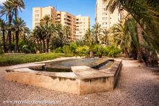 Palmeral van Elche - De cascade fontein in de Palmeral van Elche, op de achtergrond de gebouwen in de stad Elche. De Palmeral van Elche is een groene oase in de...