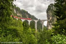 Rhätische Bahn in het Albula / Bernina landschap - Rhätische Bahn in het Albula / Bernina landschap: Een rode trein op het Landwasserviaduct bij Filisur. Het 65 meter hoge viaduct is...