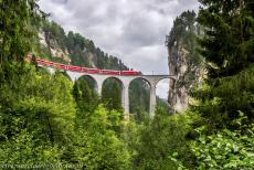 Rhätische Bahn in het Albula / Bernina landschap - Rhätische Bahn in het Albula / Bernina landschap: Een rode trein op het Landwasserviaduct bij Filisur. Het 65 meter hoge viaduct is...
