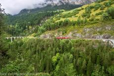 Rhätische Bahn in het Albula / Bernina landschap - Rhätische Bahn in het Albula / Bernina landschap: Een rode trein nadert de tunnel tussen het 36 meter hoge Schmittentobelviaduct en 65...