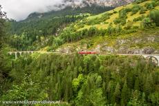 Rhätische Bahn in het Albula / Bernina landschap - Rhätische Bahn in het Albula / Bernina landschap: Een rode trein nadert de tunnel tussen het 36 meter hoge Schmittentobelviaduct en 65...